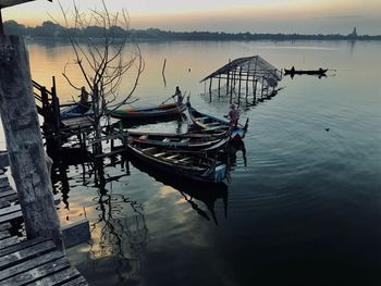 Fishing boat moored in lake against sky during sunset