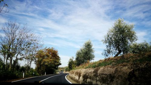 Road amidst trees against sky