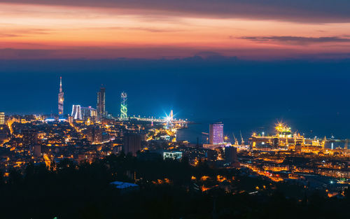 Illuminated cityscape against sky at night