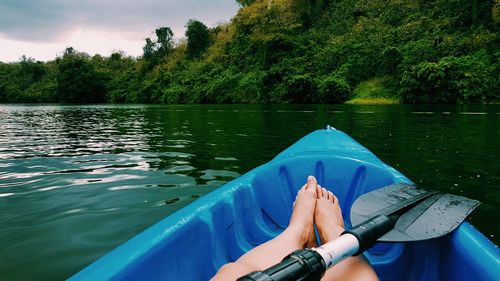 Low section of woman in blue kayak on lake