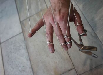 Cropped hand with strings over flooring