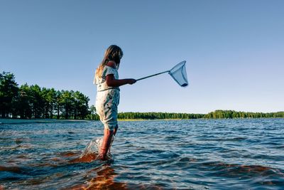 Girl standing in lake against sky