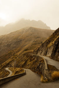 Scenic view of road by mountains against sky