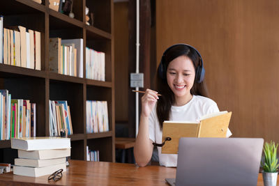 Young woman using laptop while sitting on table