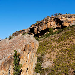 Low angle view of rock formations against clear blue sky