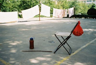 Empty chairs on road against trees in city