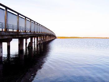 Bridge over calm sea against clear sky