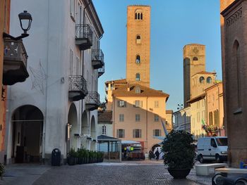 Street amidst buildings and medieval towers in city against sky