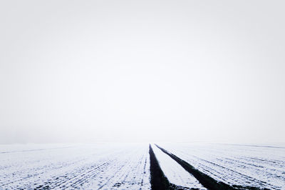 Snow covered landscape against clear sky