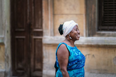 Portrait of a smiling young woman standing against building