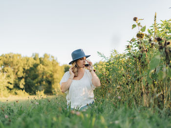 Young woman standing on field against sky