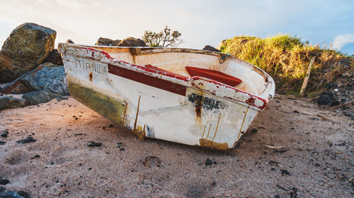 Abandoned boat on beach against sky