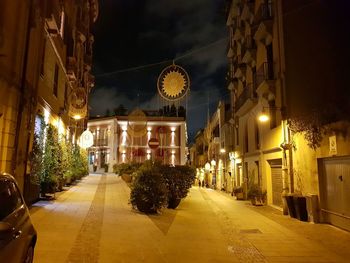 Illuminated street amidst buildings at night