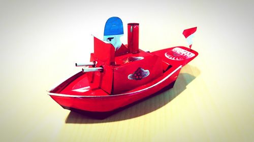 Close-up of red toy car on table against wall