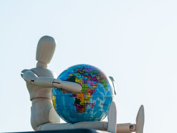 Low angle view of figurine against sky over white background