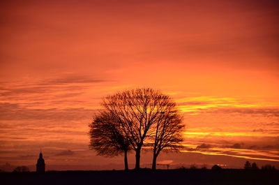 Silhouette tree on field against romantic sky at sunset