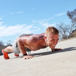 Side view of young man exercising at beach