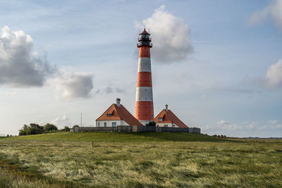 Lighthouse on field against sky