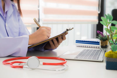 Midsection of woman using laptop on table