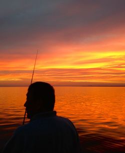 Silhouette of man in sea at sunset