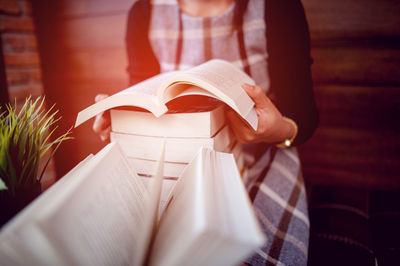 Midsection of woman reading book at home