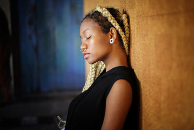 Young woman standing by wooden wall