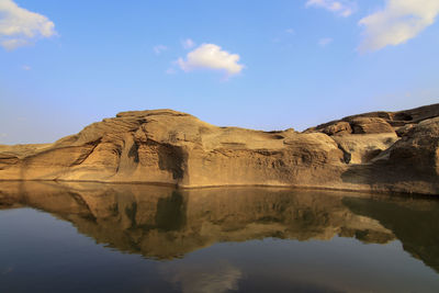 Scenic view of lake by rock formation against sky