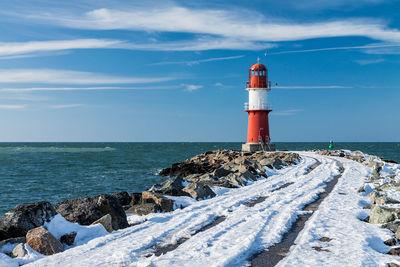 Lighthouse on beach against sky