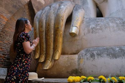 Side view of woman praying in temple
