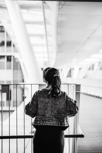 Rear view of woman standing by railing outdoors