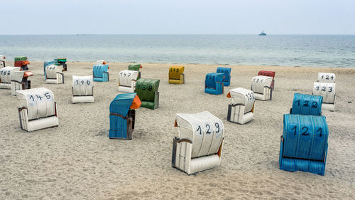 Hooded chairs on beach against sky