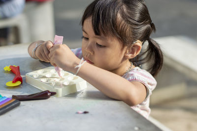 Close-up of cute girl playing with childs play clay at table outdoors