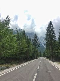 Road by trees against sky