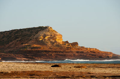 Rock formation on beach against clear sky