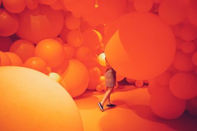 Low section of woman walking by illuminated balloons