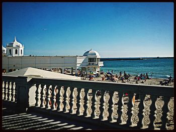 People in sea against clear blue sky