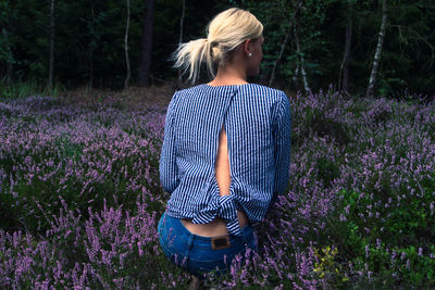 Rear view of young woman sitting on field