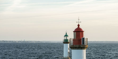 Lighthouse by sea against sky