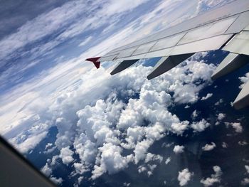 Cropped image of airplane flying over clouds