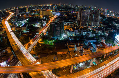 High angle view of illuminated street amidst buildings in city at night