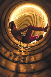Side view of man leaning in illuminated tunnel
