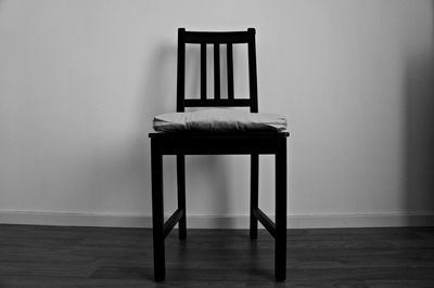 Empty wooden chair by wall at home