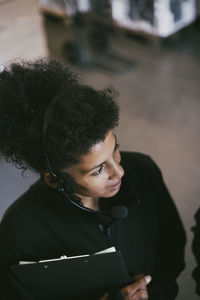 High angle view of female entrepreneur with headset looking away while working in warehouse