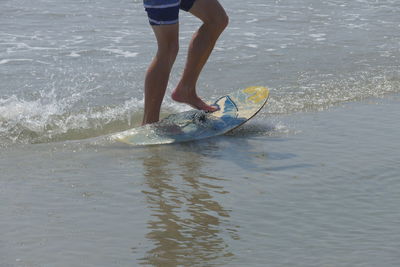 Low section of man surfing in sea