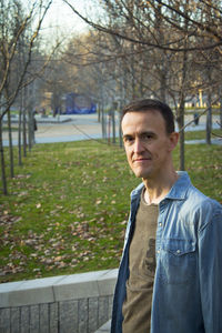 Portrait of young man standing against trees