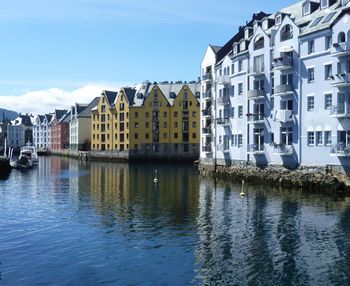 Buildings by river in town against sky