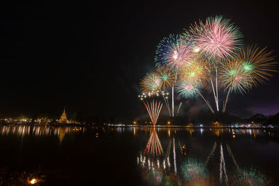 Firework display over lake at night