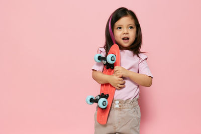 Portrait of cute girl holding toy against pink background