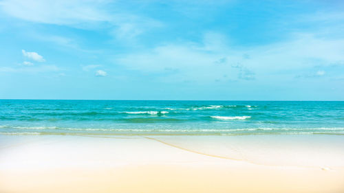 Scenic view of brown sand beach  on blue sea against sky