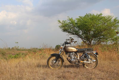 Bicycle parked on field against sky